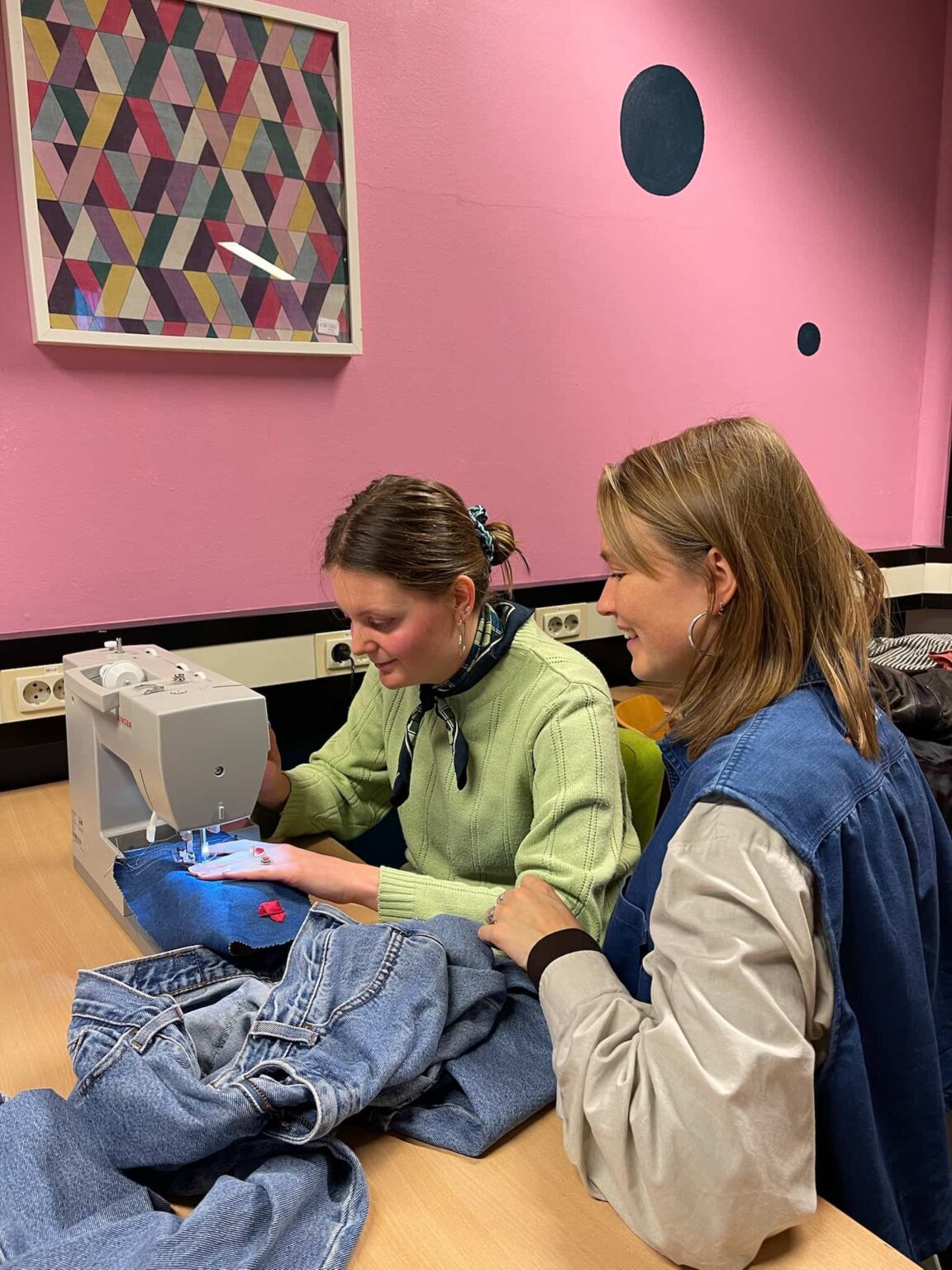 Lisan helpt deelnemer met het verstevigen van jeans achter de naaimachine.